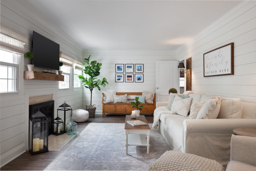 A remodeled den with white paneled walls and a fireplace