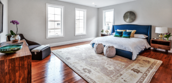 A newly remodeled bedroom with wood floors, a large rug, and charming decorations throughout.