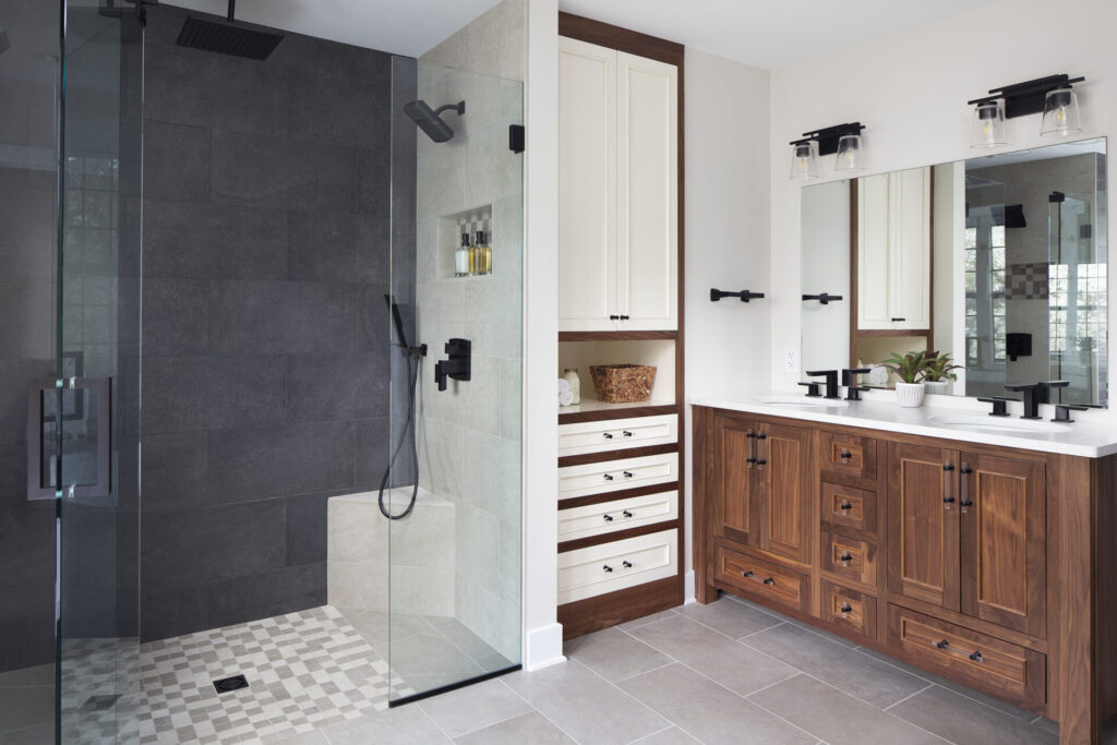 A newly-renovated modern bathroom with a walk-in shower, decorative tiles, and plenty of wooden storage cabinets